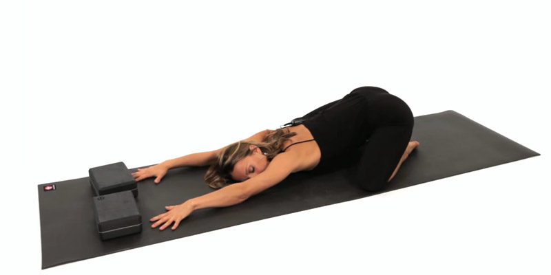 A yoga expert demonstrates child's pose on her yoga mat.