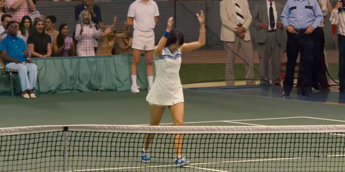 Billie Jean King throws her racquet in the air, on the tennis court.