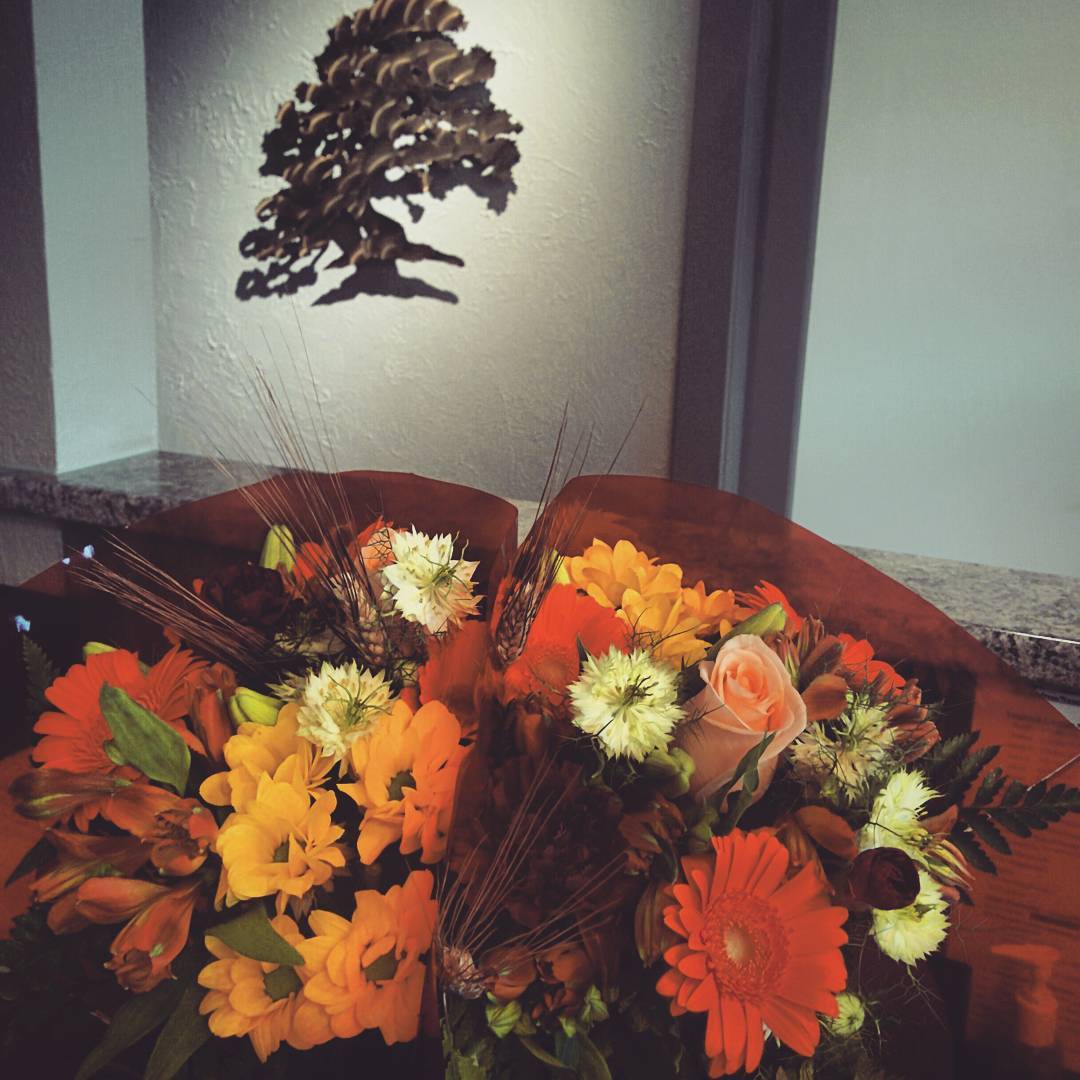 Two fall bouquets in the office, with many warm orange and brown hues.