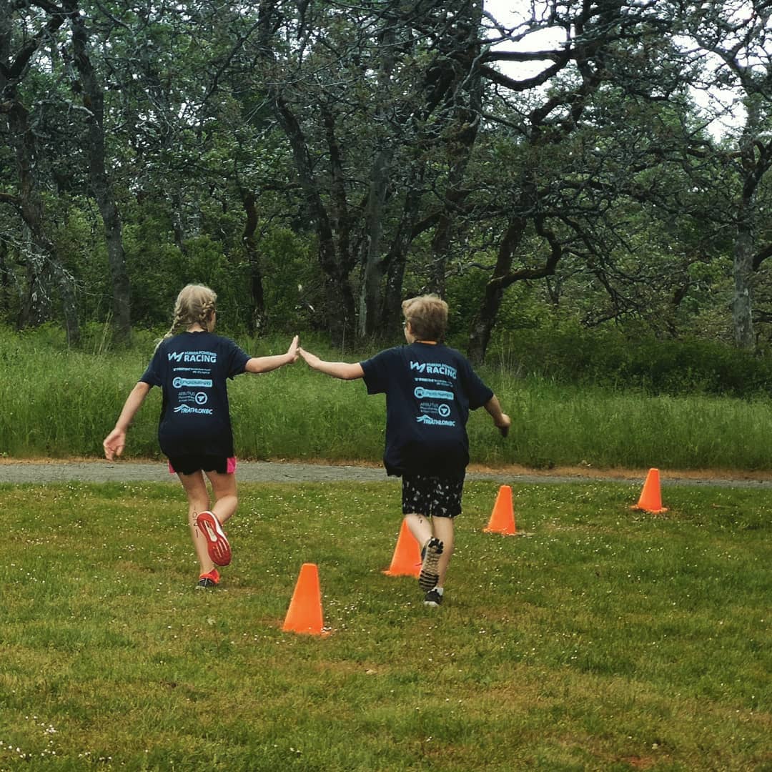 A young athlete gives a sibling a high five at the Westshore Youth Triathlon.