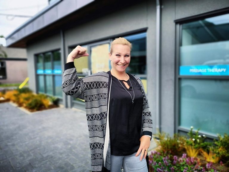 Natasha stands out front of the clinic flexing her muscles.