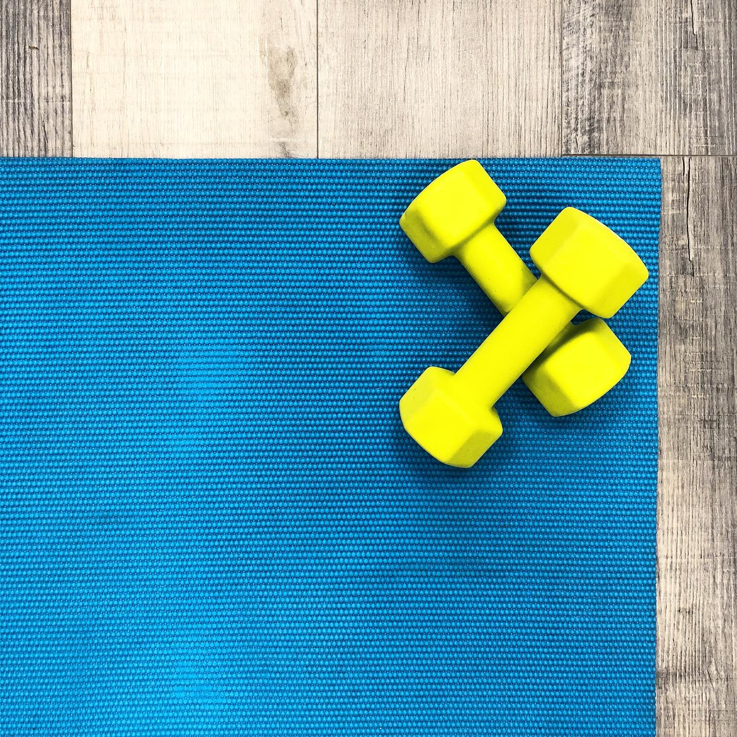 Two yellow dumbbells on a blue mat.