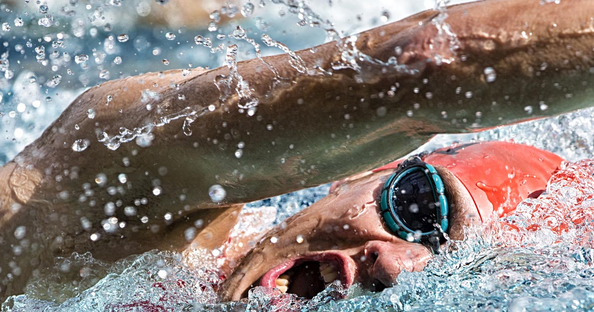 A triathlete powers through a swim stroke in the pool during a triathlon.