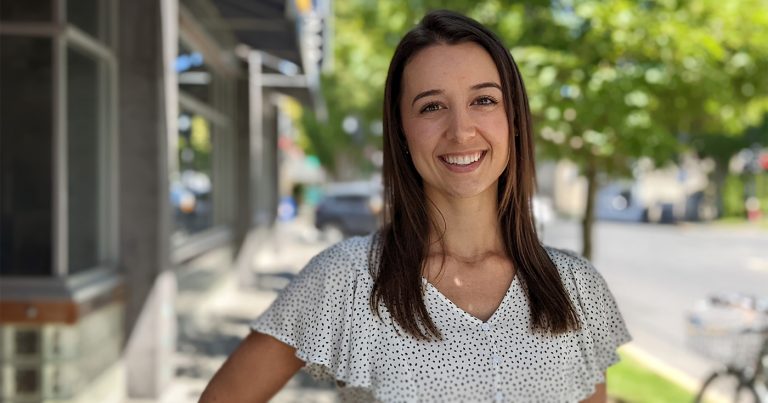 Emily Jackson, physiotherapist, on Oak Bay Ave, smiling in the sunlight.