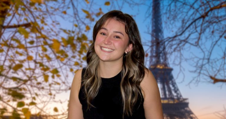 Mackenzie Wensauer smiles in a black shirt in front of the Eiffel Tower.
