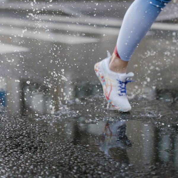 A close up of a shoe of a person running on a wet road.