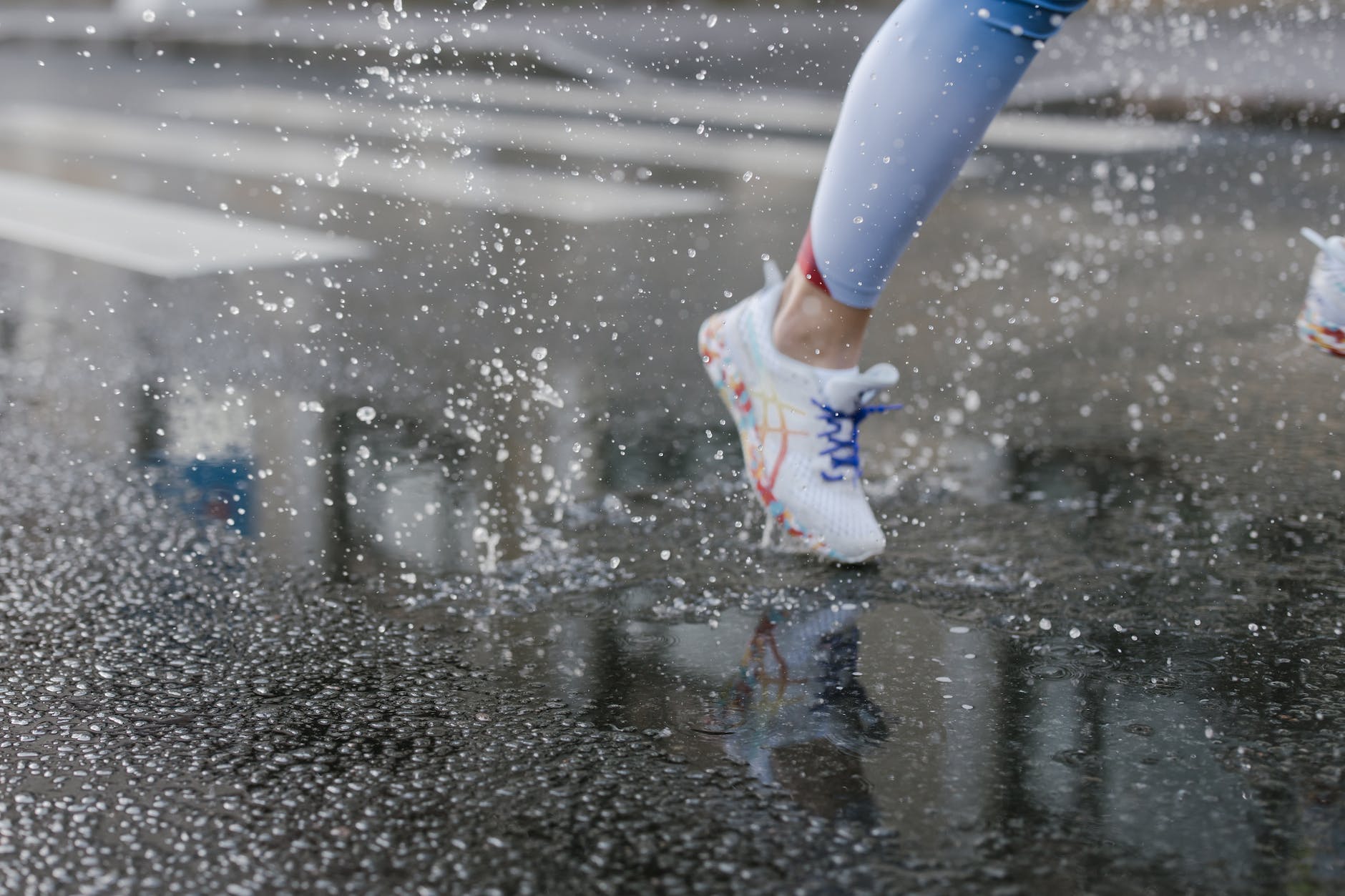 A close up of a shoe of a person running on a wet road.