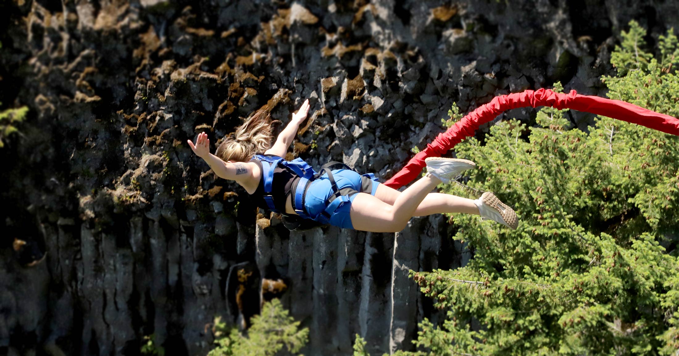 Mackenzie Wensauer bungee jumps with her arms spread out into a rocky canyone on Vancouver Island.