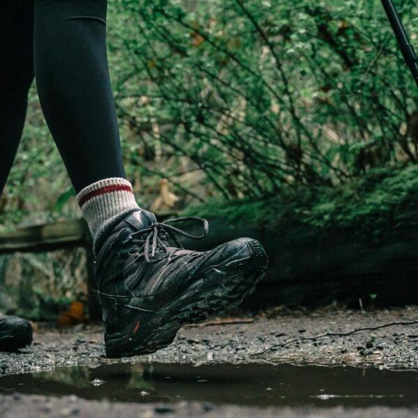A person walks on a forest path wearing black leggings and hiking boots.