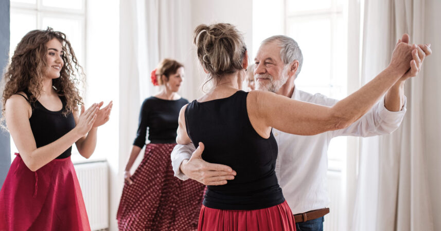 A couple dance under the watchful eye of a happy instructor.