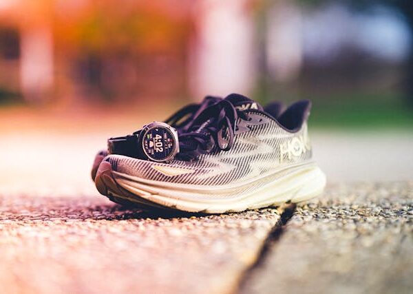 A watch sits on top of a pair of Hoka running shoes.